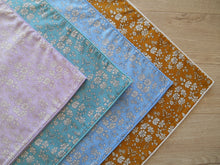Load image into Gallery viewer, Four fabric swatches in purple, blue, green, and mustard with floral patterns on a wooden surface.
